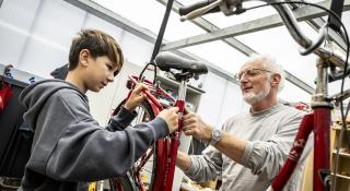 vrijwilliger repareert fiets samen met jongere
