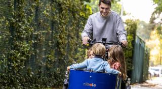 Begeleider en kinderen in bakfiets op domein in Schoten