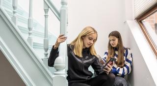 tienermeisjes zitten op een trap en kijken op hun GSM